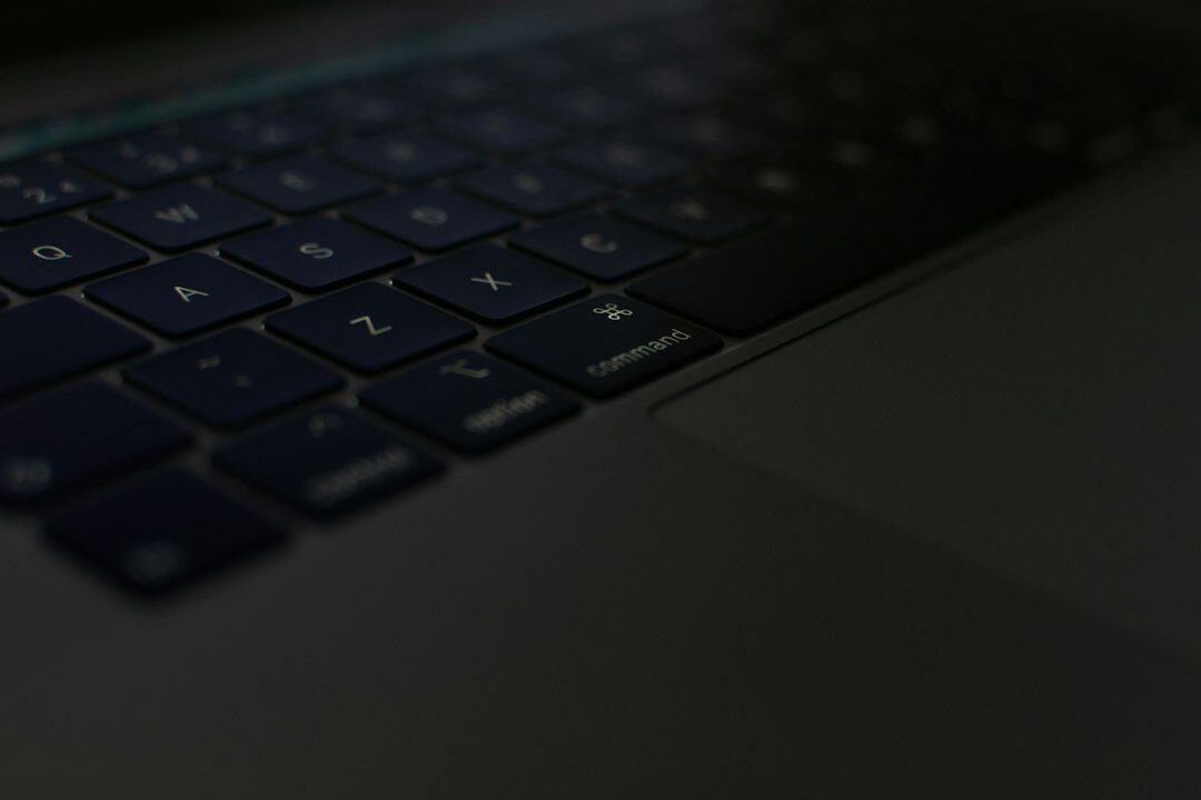 Close up of hands typing on a laptop keyboard with code on screen
